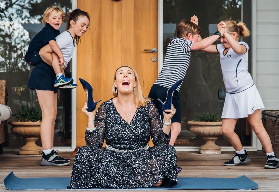 Lisa Atkinson sits on a mat holding shoes with four children behind her Frankston Arts Centre