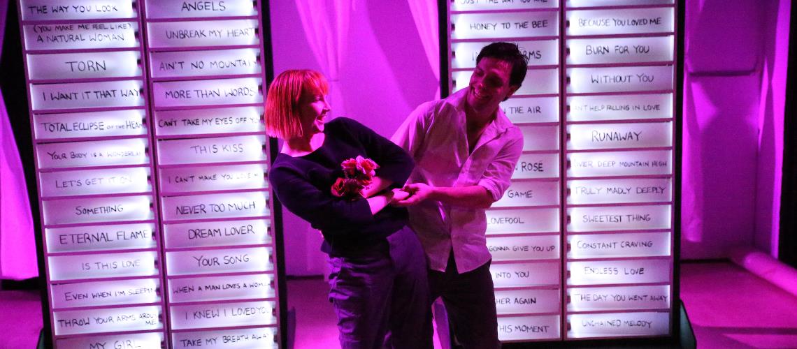 Love Song Dedications two performers link arms in front of pink backdrop lighting Frankston Arts Centre